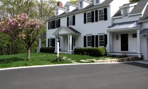 front exterior of the house with white siding and black shutters